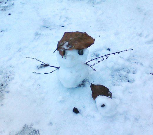 Ein kleiner Schneemann auf einem Waldweg